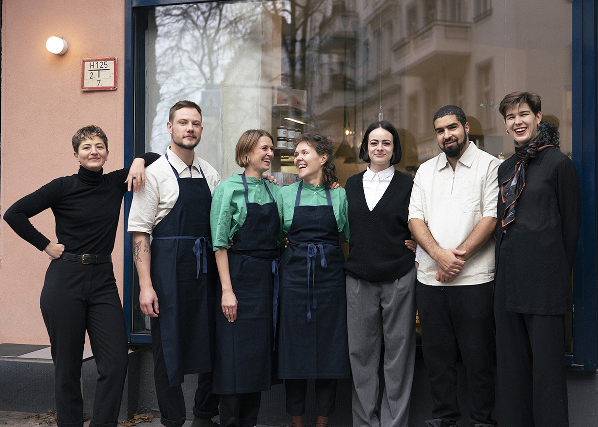 Das sieben köpfige Team des Restaurants Pars steht vor dem großen Fenster der Lokalität in Berlin