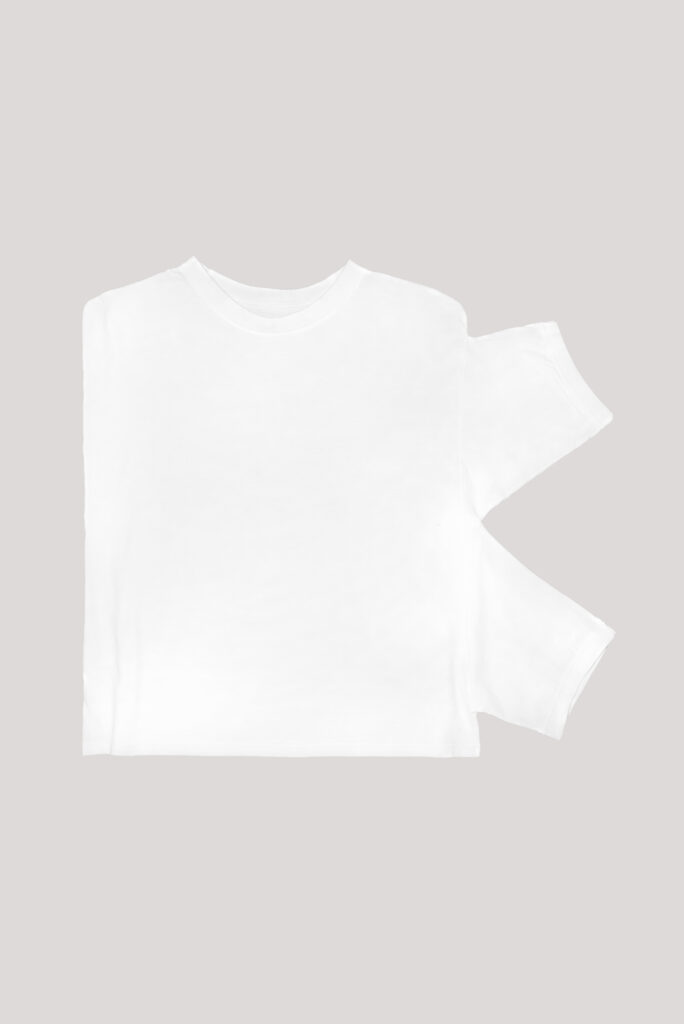 Zusammengelegtes weißes T-Shirt bei dem die Armausschnitte nur auf der rechten Seite vernäht sind.