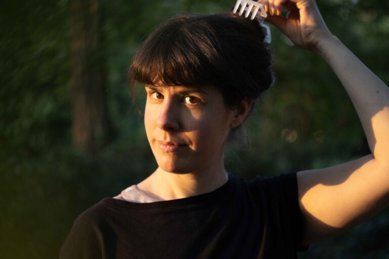 Autorin Henriette Hufgard blickt in die Kamera, während sie sich eine Haarspange an den Hinterkopf setzt.